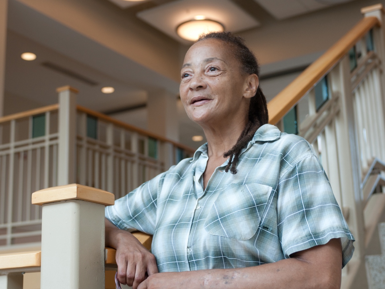 Older lady looking out on the horizon while resting on a stairway banister